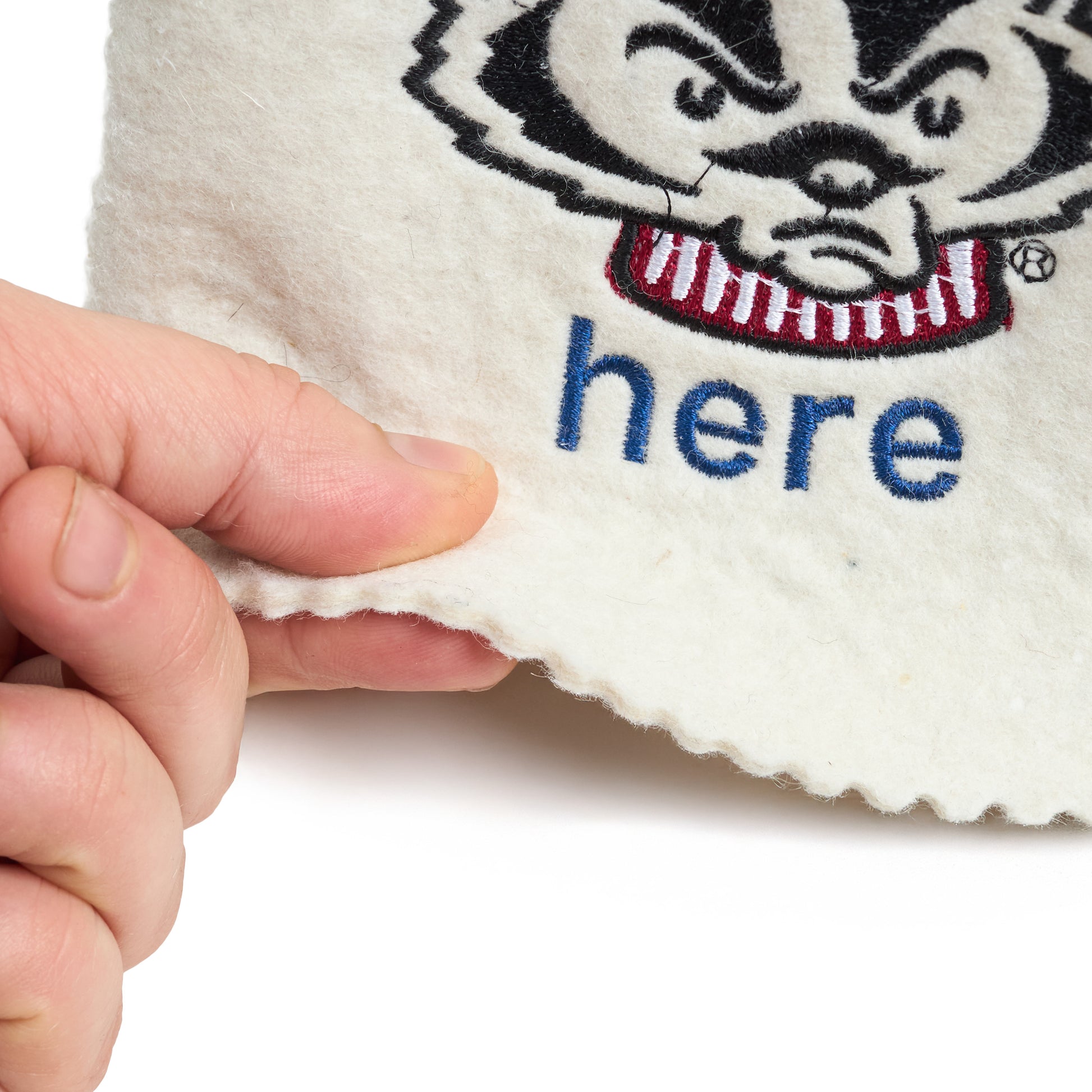 Close-up showing thickness and texture of white wool felt sauna hat with embroidered logo